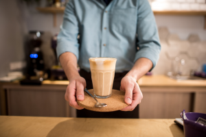 A man holding a class filled with a coffee beverage. | Coffee shops in Ellisville, MO