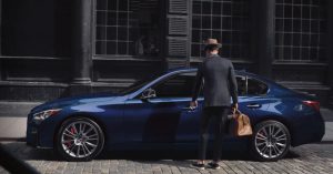 A man in a suit opening the door of a dark blue 2021 INFINITI Q50. | INFINITI dealer in Ellisville, MO