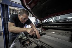 A service technician under the hood working on a vehicle. | INFINITI Service Center in Ellisville, MO.